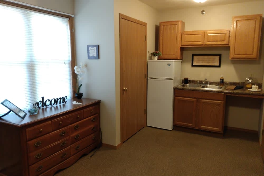 A small, cozy apartment kitchen with wooden cabinets and a fridge.