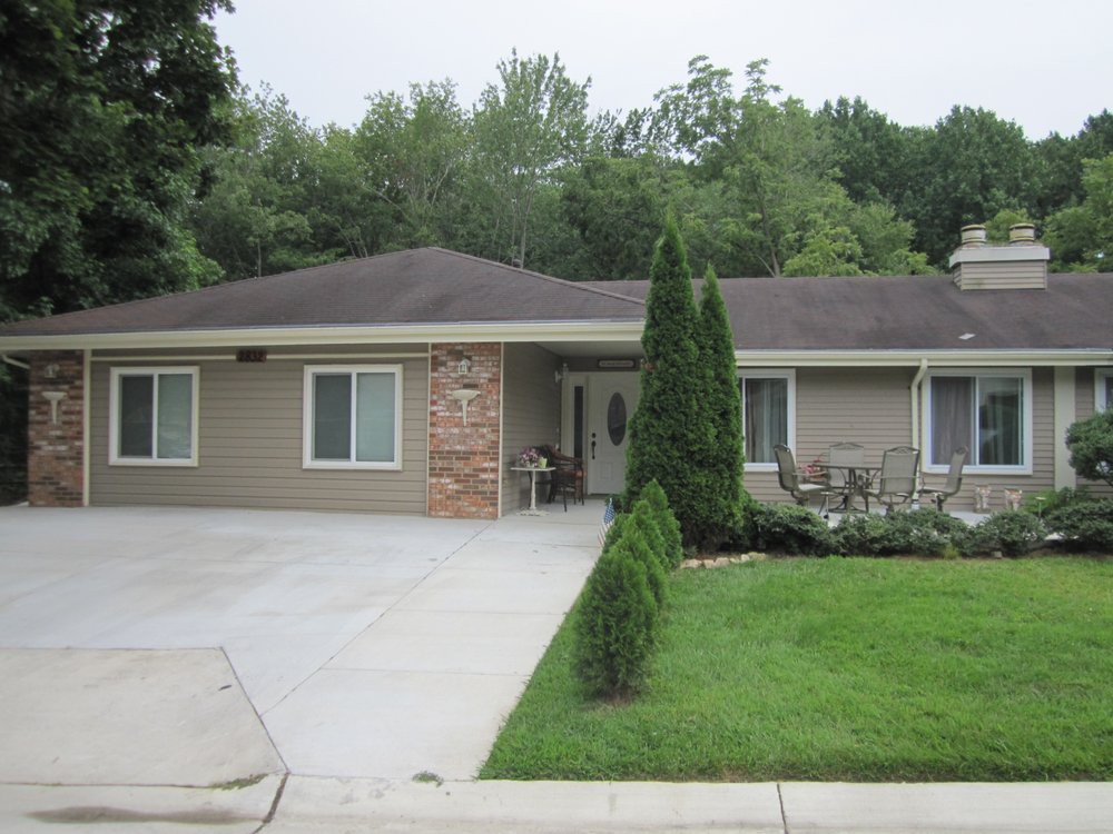 A one-story suburban house with a well-maintained lawn and trees.