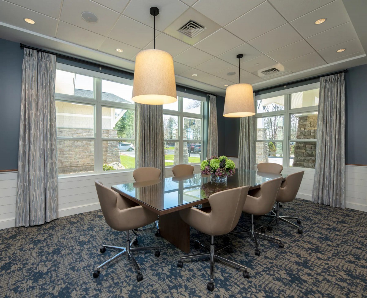 A modern conference room with a large table, chairs, and pendant lighting.