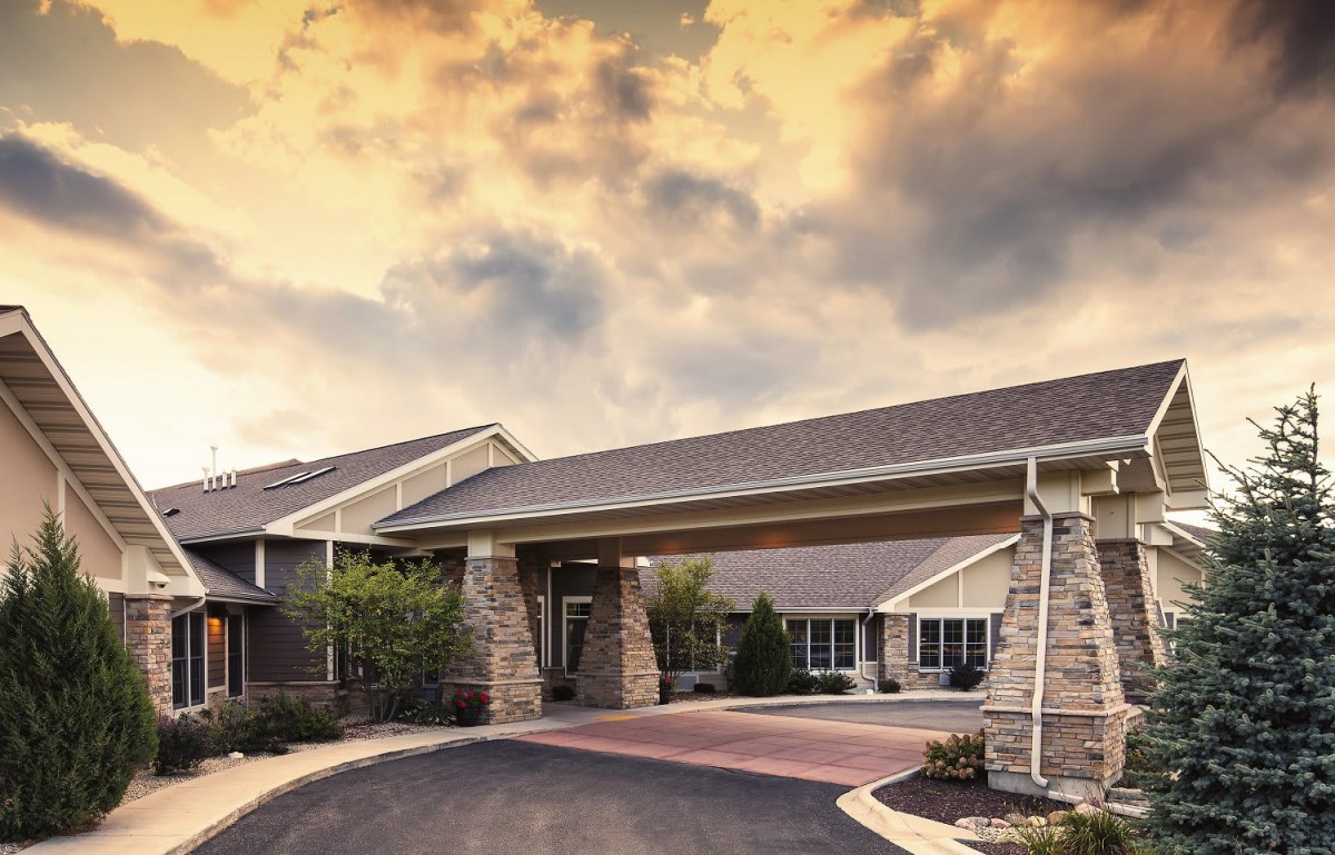 A residential building with a covered entrance under a dramatic sunset sky.