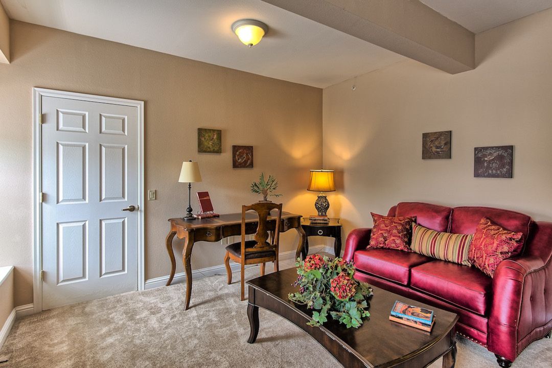 A cozy living room with a vibrant red sofa, elegant wooden furniture, and tasteful decor.