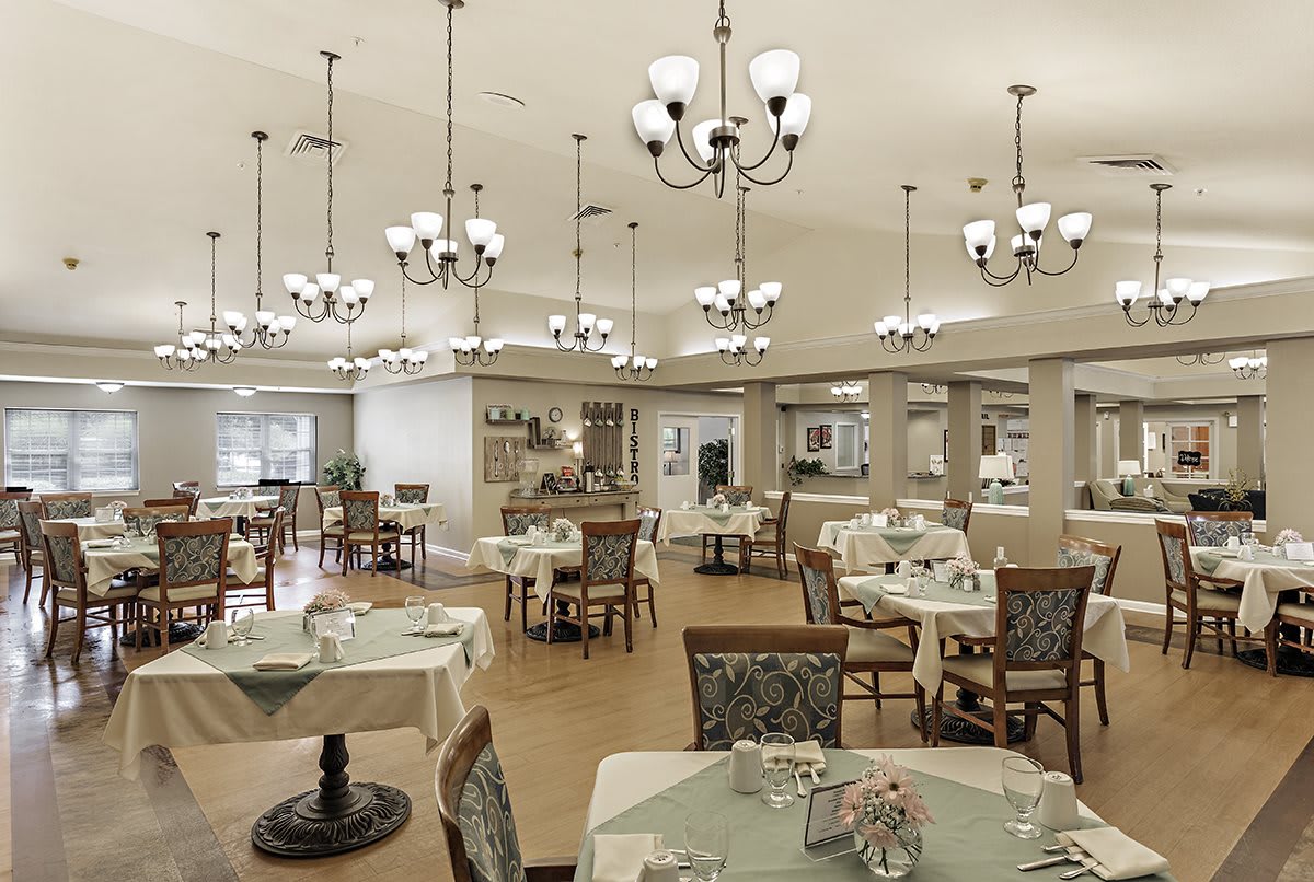 An elegant dining room with chandeliers and neatly arranged tables and chairs.