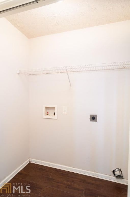 An empty laundry room with white walls and hookups ready for installation.