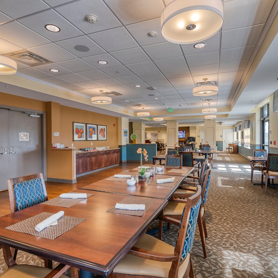 A spacious and well-lit dining area with neatly arranged tables and chairs, featuring elegant lighting fixtures.