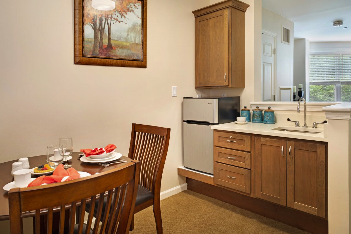 A cozy kitchen and dining area with wooden furniture and a mini fridge.