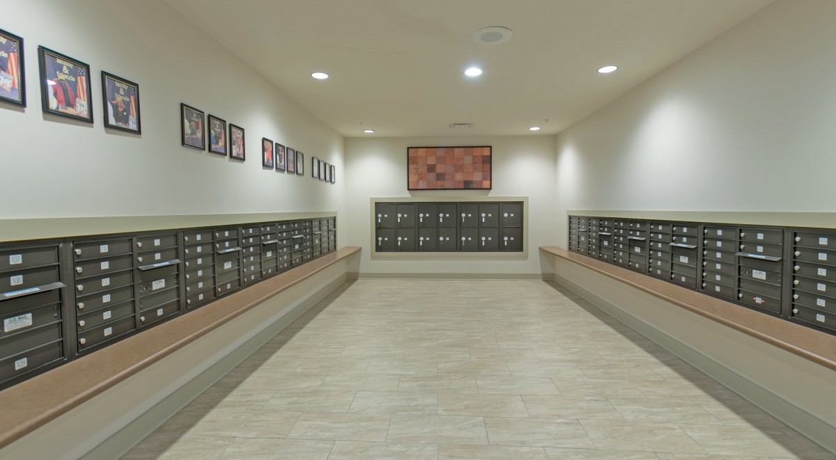 A spacious mailroom with multiple rows of mailboxes in an apartment building hallway.
