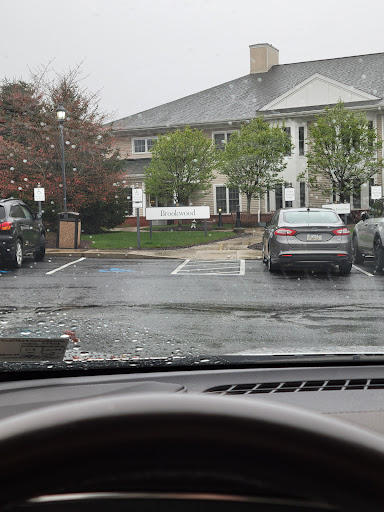 A view from inside a vehicle showing a rainy parking lot in front of an apartment complex.