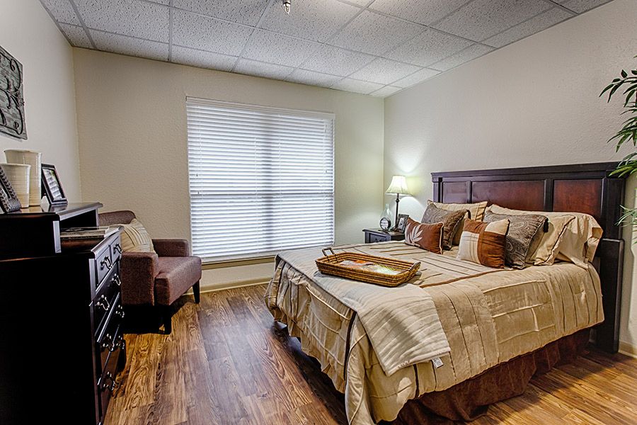 A cozy bedroom with a neatly made bed, wooden floors, and soft ambient lighting.