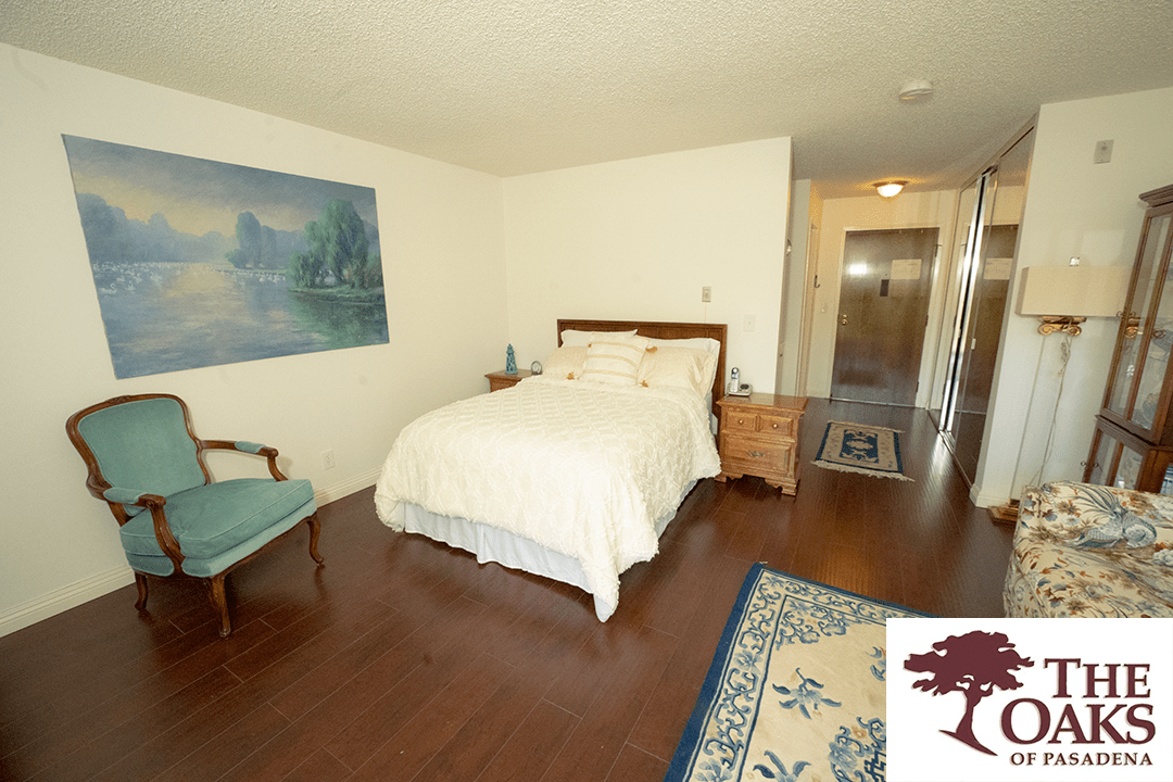 A cozy bedroom with a bed, chair, and painting on the wall.