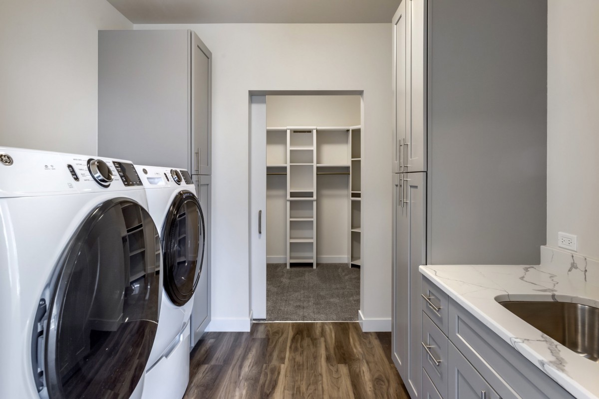 A modern laundry room with a washer, dryer, and ample shelving for storage.
