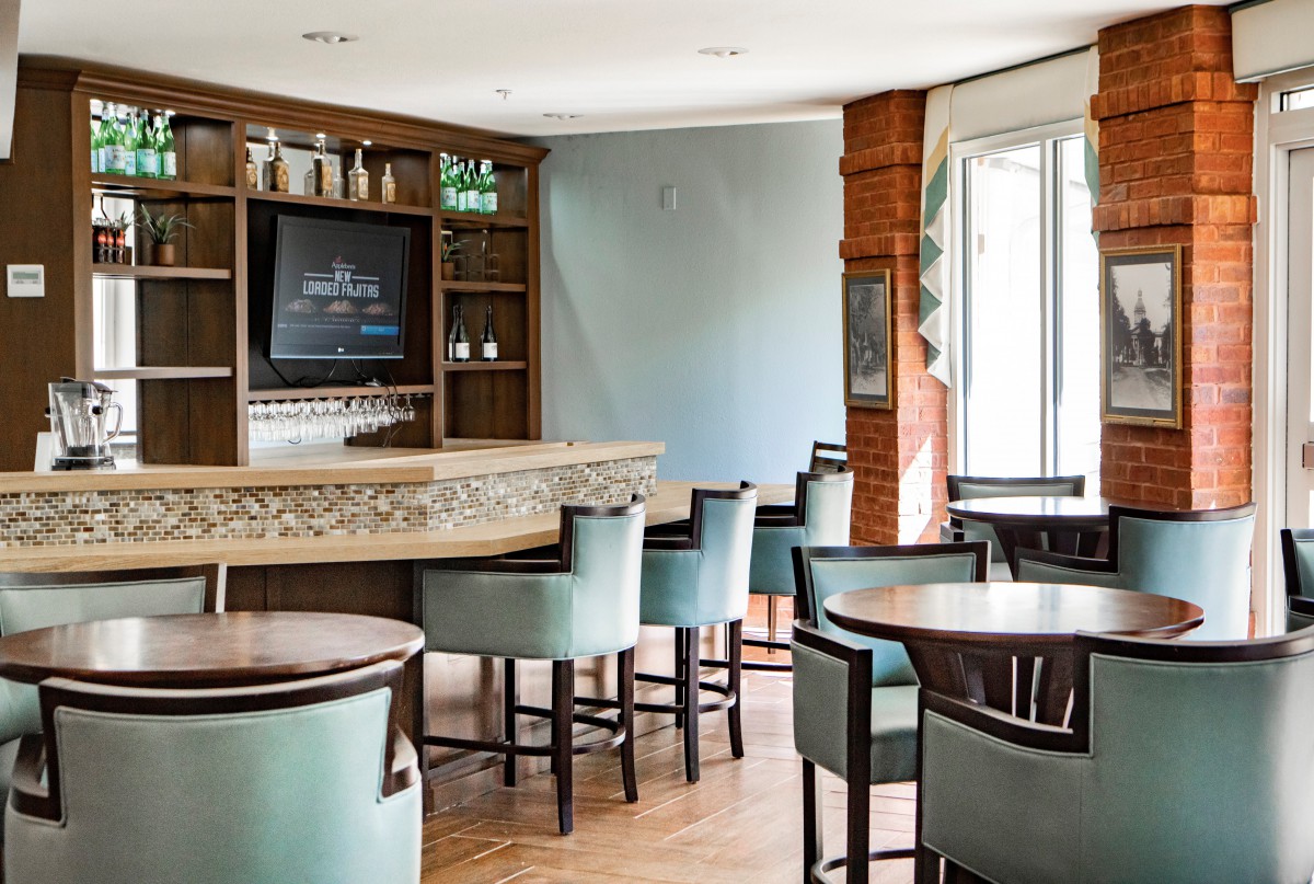 A cozy bar interior with high chairs and tables arranged around a counter.