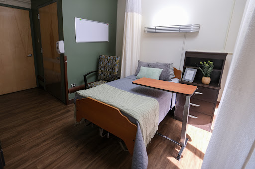 A well-designed hospital room featuring a bed, bedside table, and comfortable seating.