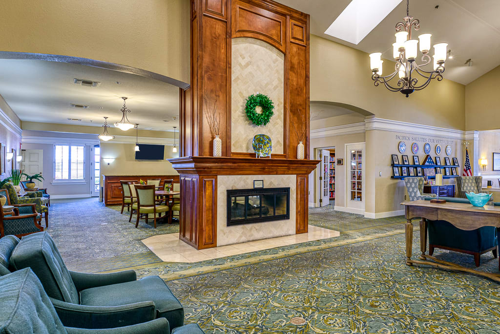 A spacious lobby featuring a central fireplace, elegant chandelier, and comfortable seating area.