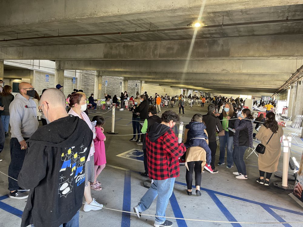 A large crowd of people standing in line inside a parking garage.