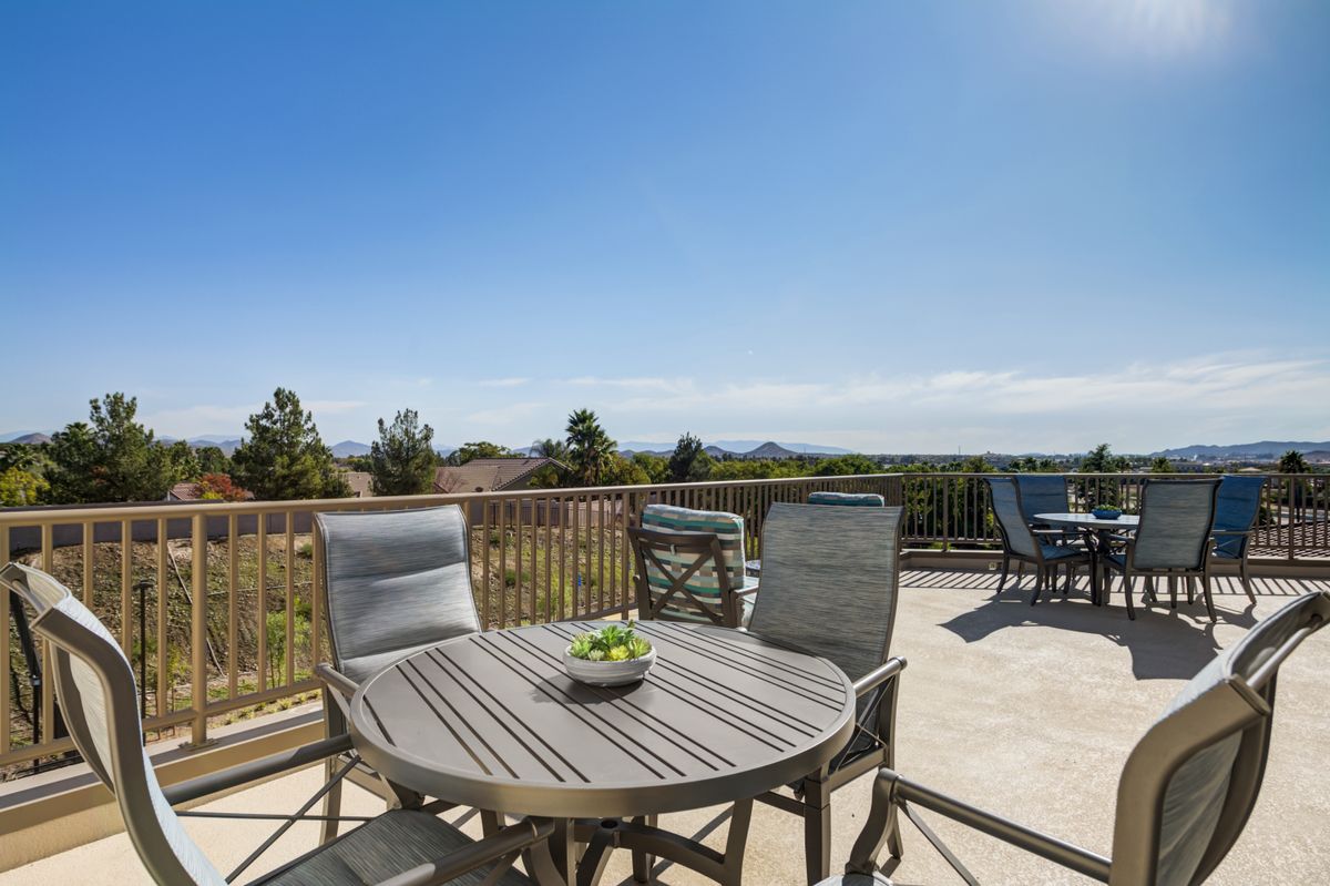 A sunny patio with outdoor furniture and a scenic view.