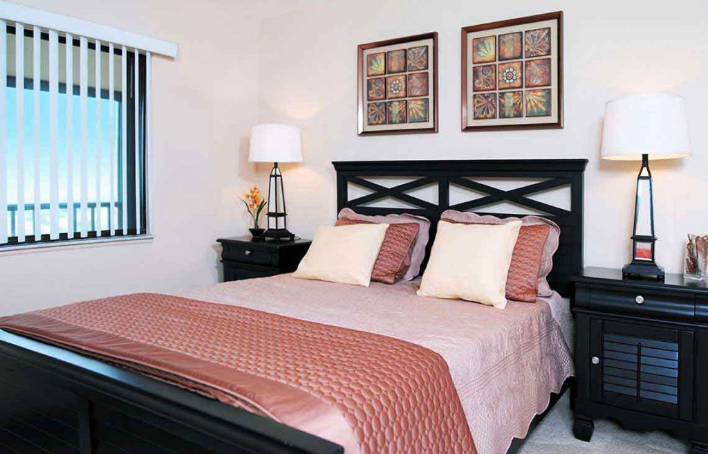 A cozy and well-decorated bedroom featuring a bed with patterned pillows and framed artwork on the wall.