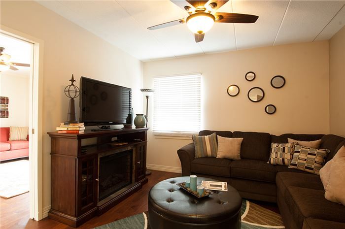 A cozy living room with a sofa, television, and decorative wall clocks.