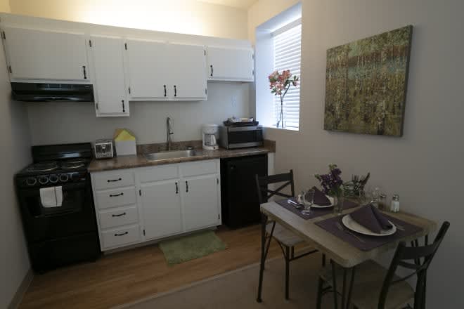 A cozy kitchen with white cabinetry and a small dining area.