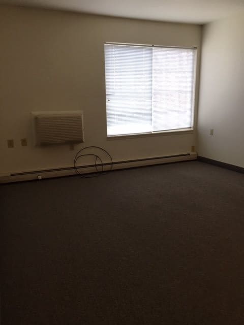 An empty room with carpet flooring and a large window.