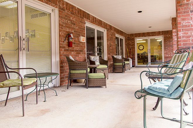 A cozy patio with comfortable outdoor seating and tables against a brick wall.