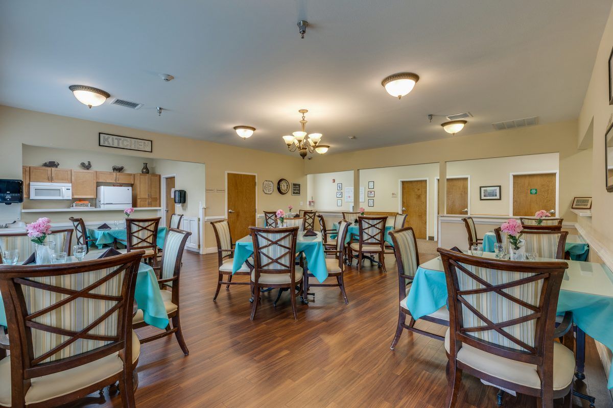 A spacious dining room with elegantly set tables and bright lighting.