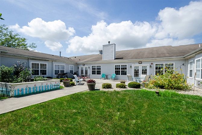A spacious residential house with a large patio and well-maintained yard under a cloudy sky.