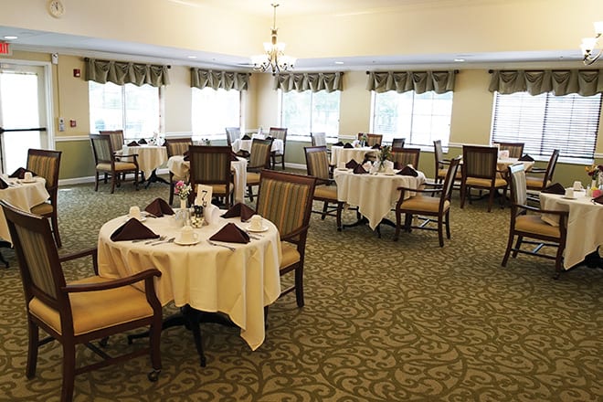 An elegant dining room with neatly arranged tables and chairs, featuring chandeliers and stylish decor.