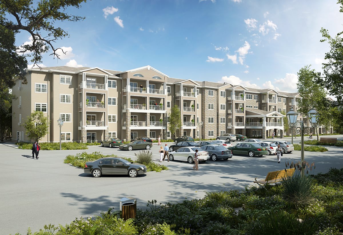 A multi-story apartment building with a surrounding parking lot filled with cars under a clear blue sky.