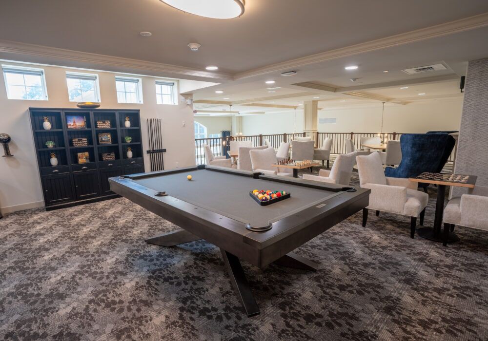 A modern recreation room featuring a sleek pool table and comfortable seating areas.