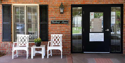 The welcoming entrance of Woodlawn House featuring white furniture and a brick facade.
