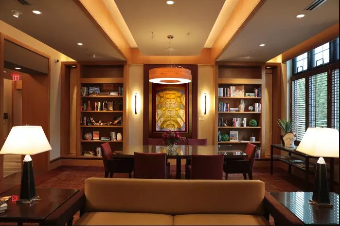 A cozy library with wooden bookshelves, comfortable seating, and warm lighting.