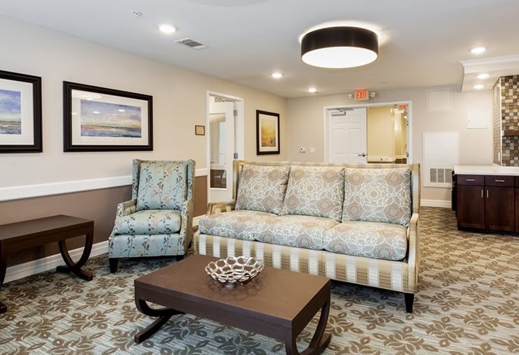 A stylish living room with a patterned sofa, matching armchair, and a wooden coffee table under contemporary lighting.