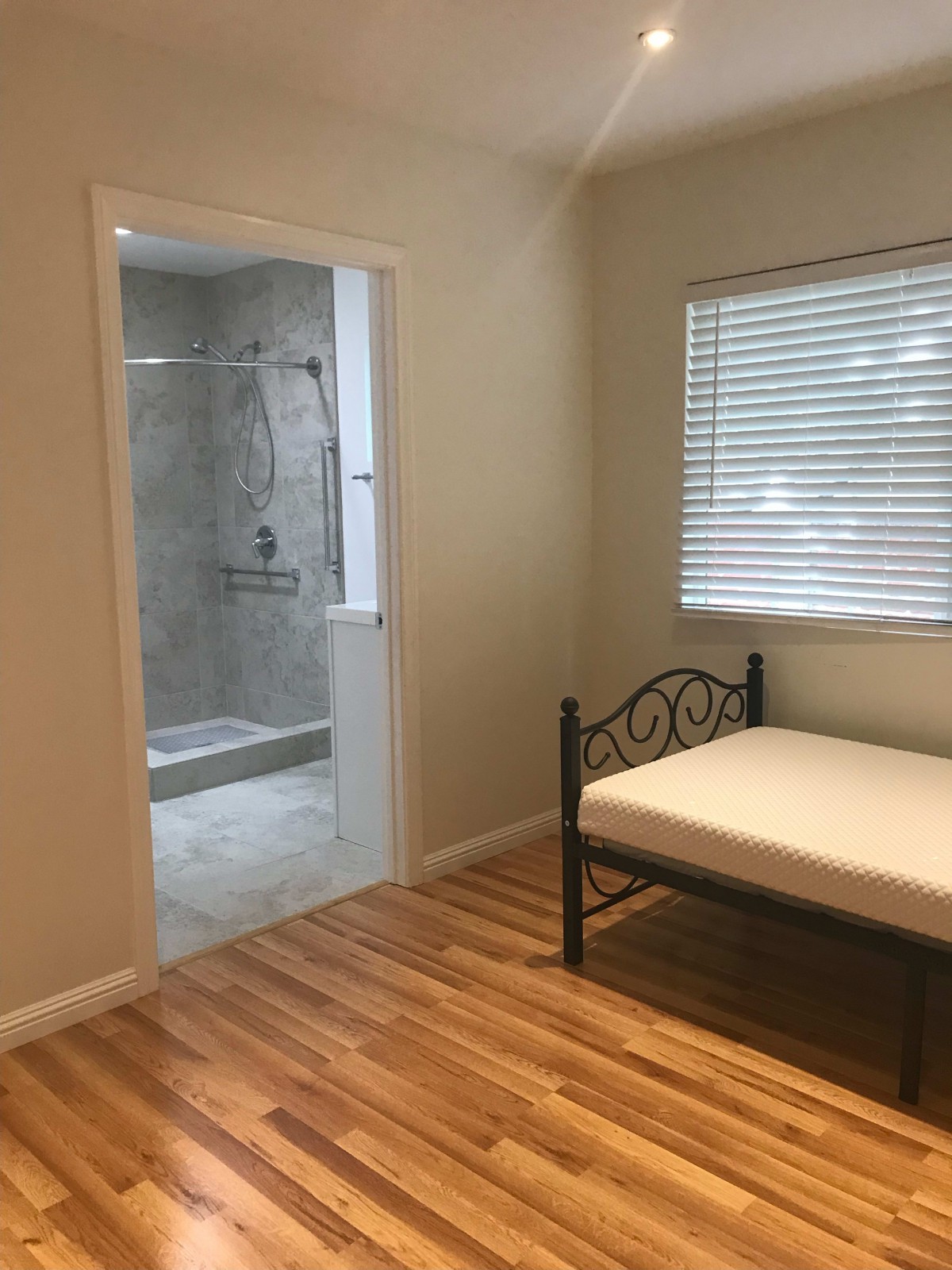 A cozy bedroom with a single bed and a view into an adjacent bathroom.