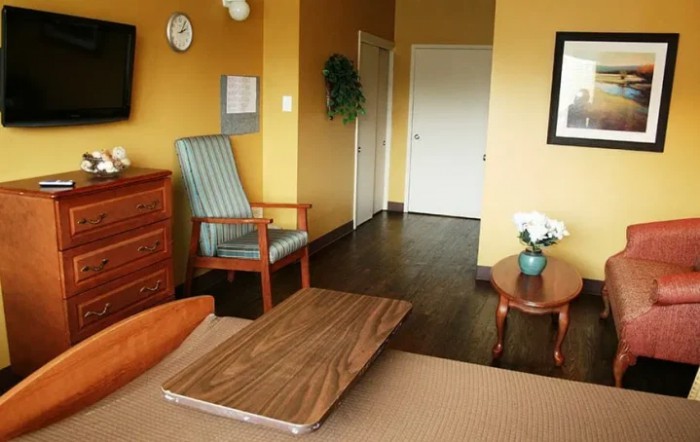 A cozy hotel room featuring a comfortable chair, wooden furniture, and decorative elements.