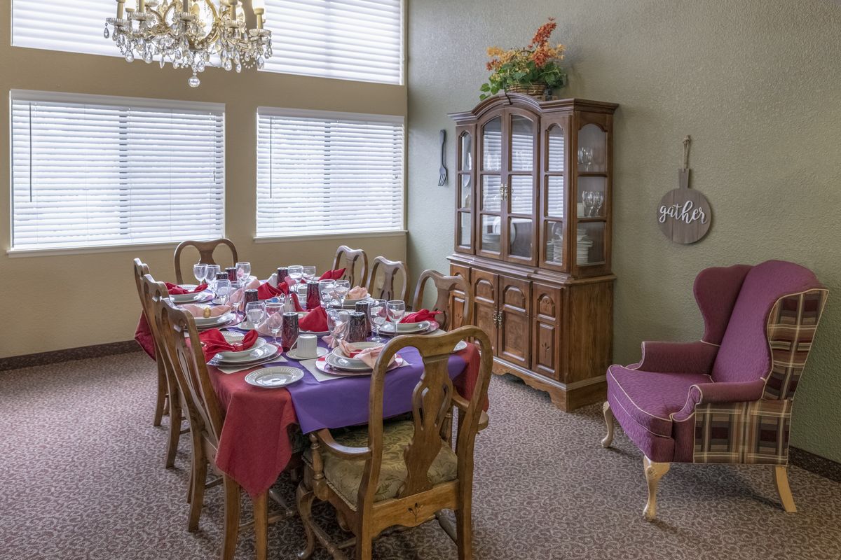 A dining room with a long table set for a meal, featuring a chandelier and china cabinet.