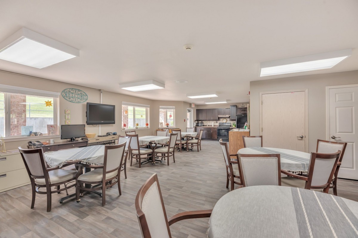 A spacious, well-lit dining area with multiple tables and chairs arranged for community gatherings.