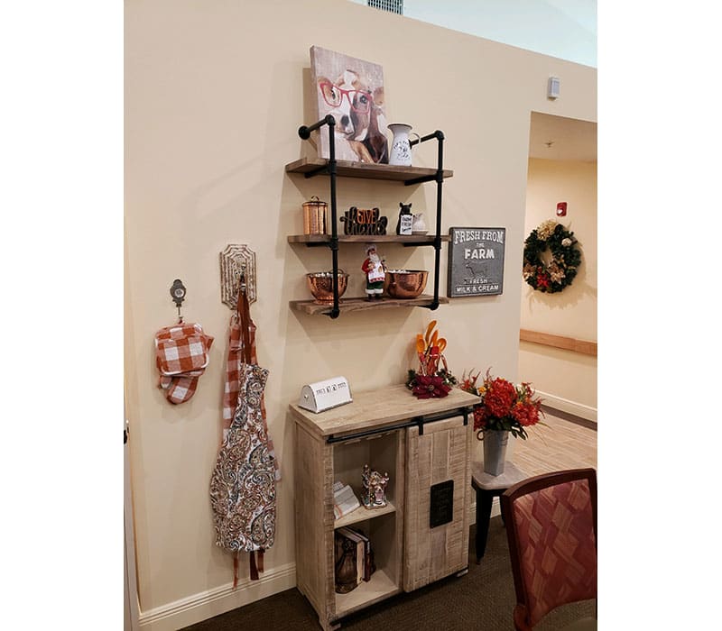 A cozy interior corner featuring decorative shelves, a cabinet, and festive wall hangings.