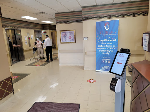 A lobby area featuring an information kiosk, a congratulatory banner, and people waiting near the elevator.
