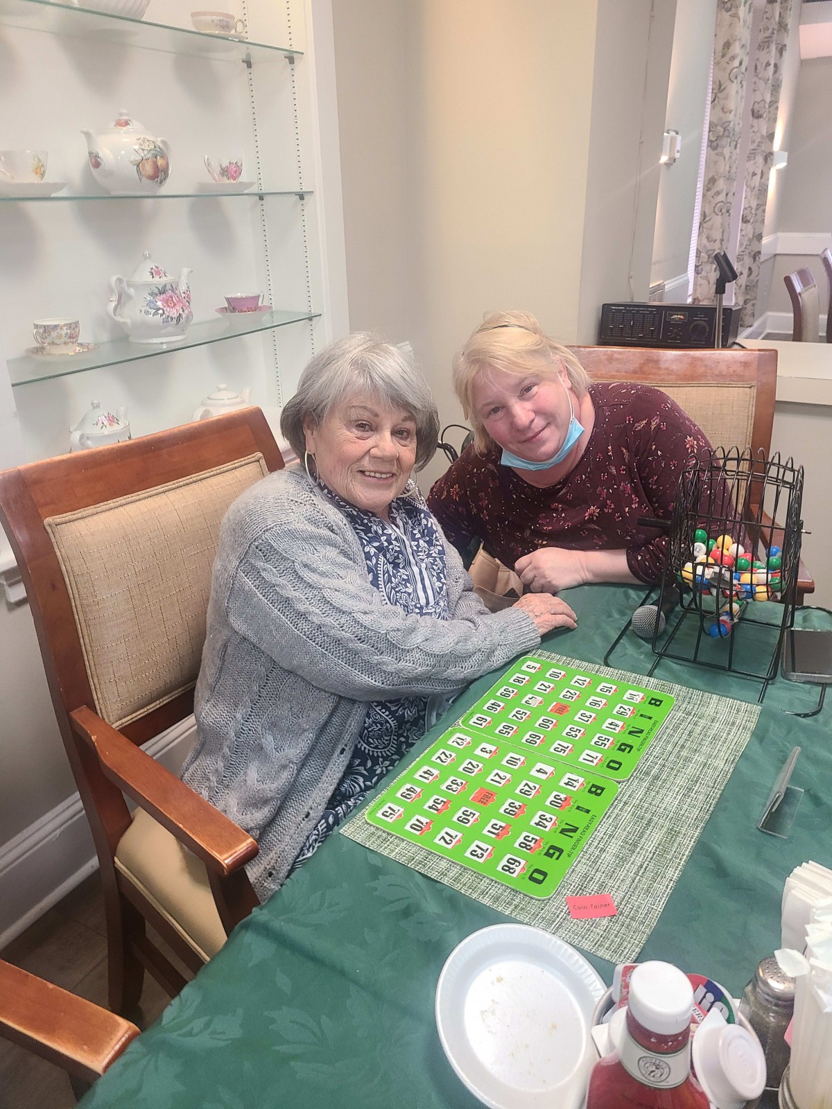 Two elderly women enjoying a game of bingo at a table indoors.