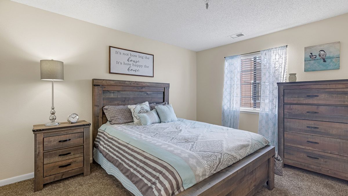 A cozy bedroom with a neatly made bed, featuring soft bedding and a bright window.