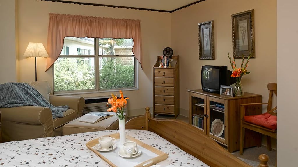 A cozy bedroom with a bed, dresser, and an old-style television.