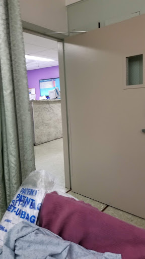 A view of a hospital doorway leading to a waiting area with purple walls.