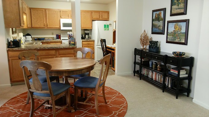 A cozy dining area with a wooden table, chairs, and a view into the kitchen.