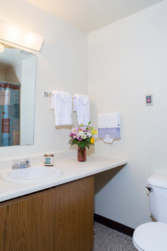 A clean and well-organized bathroom featuring a vanity area with a mirror, towels, and a vase of fresh flowers.
