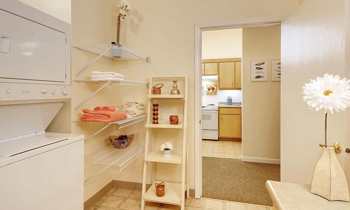 A cozy bathroom with neatly organized shelves and a view into the kitchen.