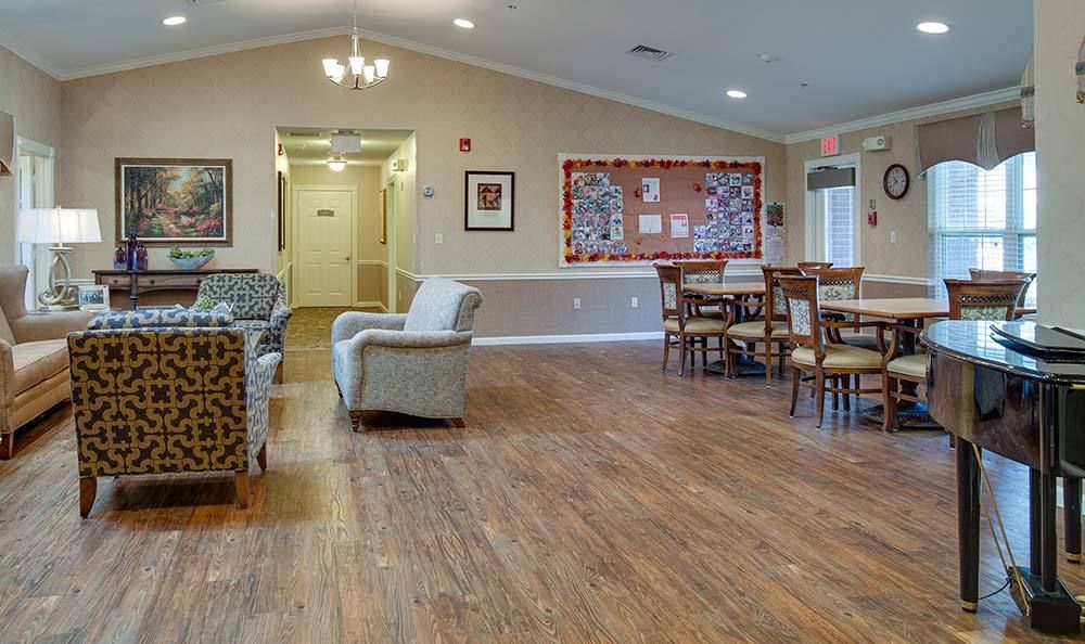 A cozy community room featuring plush seating and a hardwood floor.