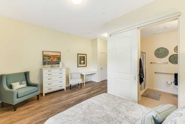 A cozy bedroom featuring a dresser, chair, and desk with decorative artwork on the walls.