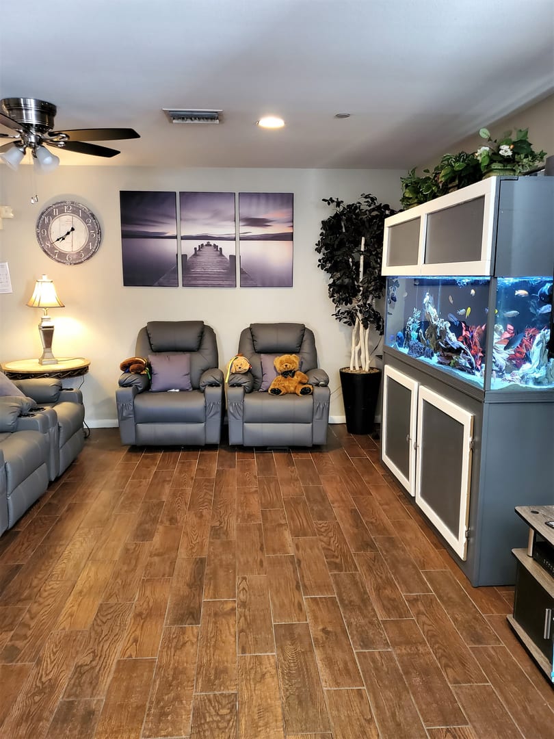 A cozy living room featuring recliner chairs, a large fish tank, and stylish wall art.