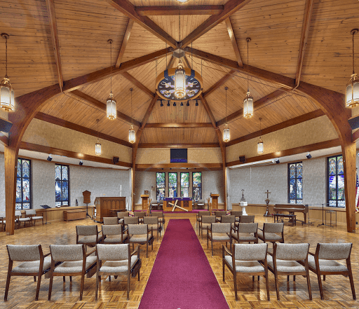 A beautifully designed interior of a ceremony space featuring wooden beams, ample seating, and soft lighting.