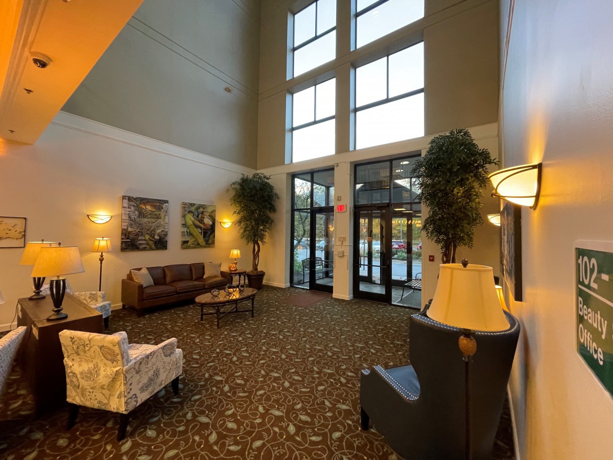 A cozy lobby with comfortable seating, large windows, and warm lighting.